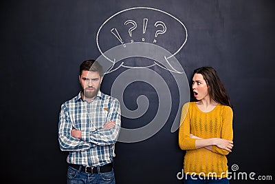 Frowning couple standing after argument over chalkboard background Stock Photo