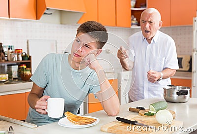 Frowning teen boy with disgruntled grandfather Stock Photo