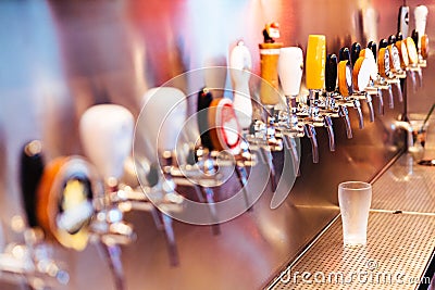 Frozen beer glass with beer taps with nobody. Selective focus. Alcohol concept. Vintage style. Beer craft. Bar table. Steel taps Stock Photo