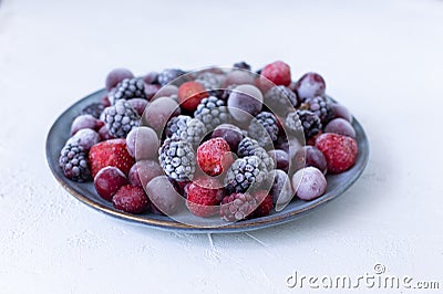 Frozen berries in a gray plate on a white background. Stock Photo