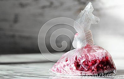 Frozen berries of viburnum cranberry on a gray background. Storage of frozen food. Red frozen cranberries or viburnums in a bag on Stock Photo