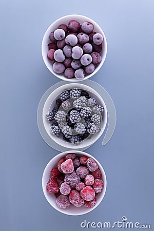 Frozen berries in a white bowls on a gray background. Stock Photo