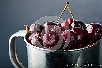 Frozen cherries in a metal cup on a dark grey background. Toned, dark moody. Stock Photo