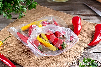 Frozen chili pepper on a wooden board on the table. Frozen vegetables. Frozen food Stock Photo