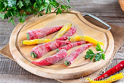 Frozen chili pepper on a wooden board on the table. Frozen vegetables. Frozen food Stock Photo