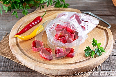 Frozen chili pepper on a wooden board on the table. Frozen vegetables. Frozen food Stock Photo