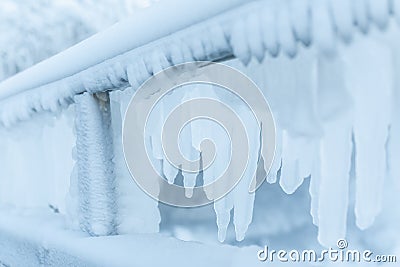 Frozen fence in winter. Huge icicles Stock Photo