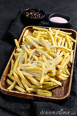 Frozen French fries in a wooden bowl. organic potatoes. Black background. Top view Stock Photo