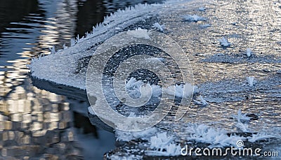 Frozen and icy part of the river in winter makes a layer of ice near the shore, snowflakes are like fluffy needles Stock Photo