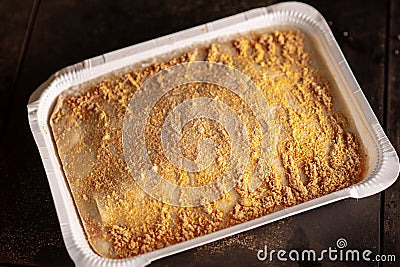 Frozen lasagna in paper form on a dark background. Semifinished Stock Photo