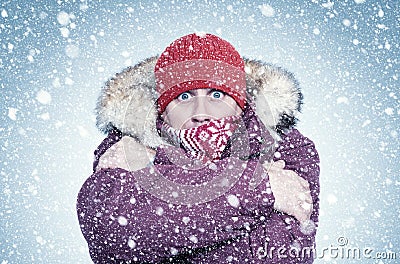 Frozen man in red winter clothes warms his hands, cold, snow, frost, blizzard Stock Photo