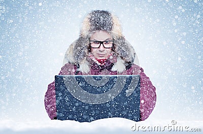 Frozen man in red winter clothes working on a laptop in the snow. Cold, frost, blizzard Stock Photo