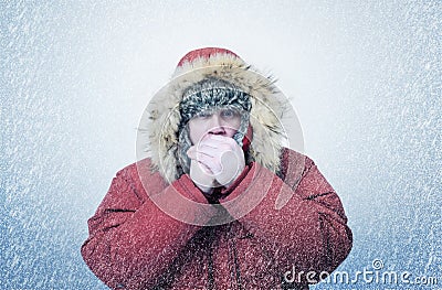 Frozen man in winter clothes warming hands, cold, snow, blizzard Stock Photo