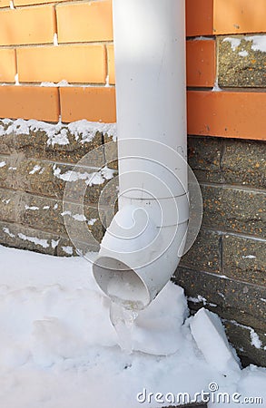 Frozen Rain Water Draining Gutter Downpipe. Gutter Spout in Winter. Stock Photo