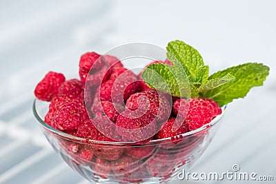 Frozen raspberries in a glass piala and a sprig of mint Stock Photo