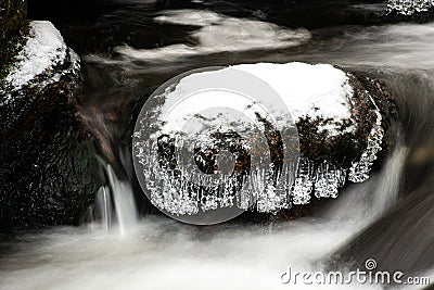 Frozen rock in a snowy stream, silky water around Stock Photo