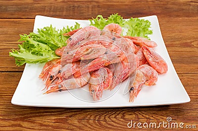 Frozen shrimps with lettuce on dish closeup on old table Stock Photo