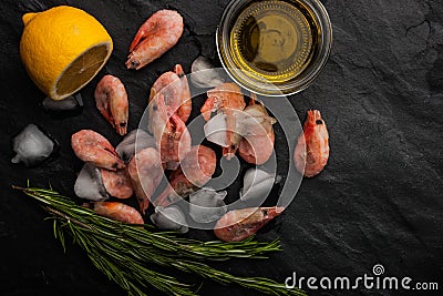 Frozen shrimps with rosemary, lemon and olive oil on the black stone table horizontal Stock Photo