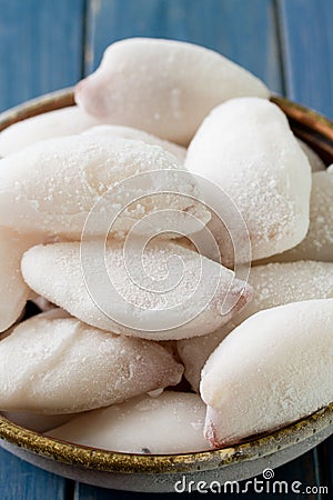 Frozen squids in dish on blue background Stock Photo