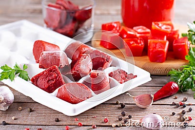 Frozen tomato paste in the plastic shape on wooden background. Life hacks, simple way to store vegetables Stock Photo