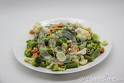 Frozen vegetables: cauliflower, green peas, leeks, broccoli, carrots, green beans on a white plate Stock Photo
