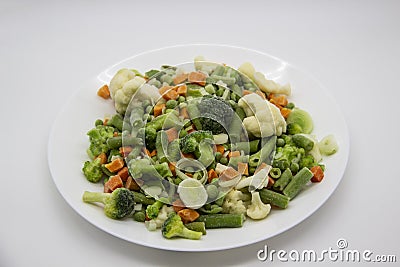 Frozen vegetables: cauliflower, green peas, leeks, broccoli, carrots, green beans on a white plate Stock Photo