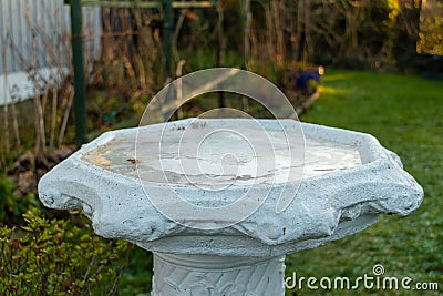 Frozen water and ice in a bird bath in a garden in the winter sun Stock Photo