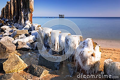 Frozen wooden breakwaters line at Baltic Sea Stock Photo