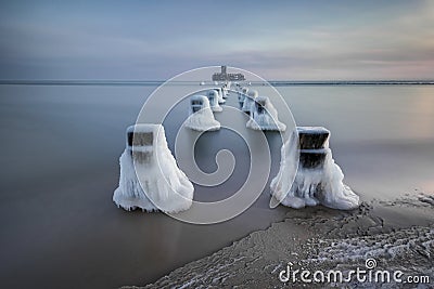 Frozen wooden breakwaters line to the world war II torpedo platform at Baltic Sea Stock Photo