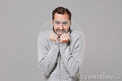 Frozen young bearded man in gray sweater posing isolated on grey background studio portrait. Healthy fashion lifestyle Stock Photo