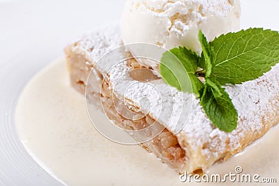 Fruit apple strudel cake served with ice cream, mint leaf and vanilla sauce. Classical austrian dessert on white plate Stock Photo