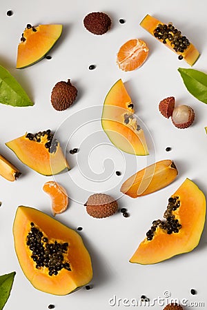 Fruit background made of pieces of ripe papaya, tangerine and litchi on a white background Stock Photo