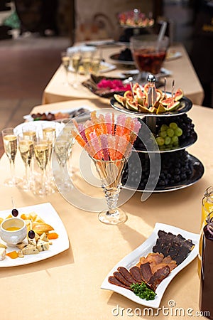 Fruit bowl with fig slices, white and black grapes, a glass with lollipops, a plate with sliced smoked meats Stock Photo