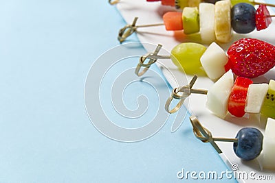 Fruit canapes. Fresh fruit canapes on white plate. Mixed fruit in white plate healthy food style, blue backgrounds. Stock Photo