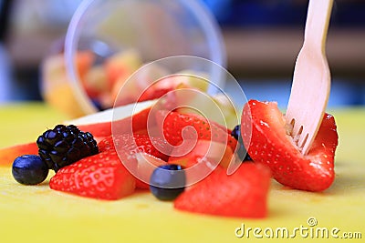 Fruit cup with a fork and spilled fruits Stock Photo