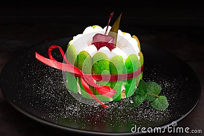 Fruit dessert tart with whipped sweet curd cream and with sweet cherry on top. Old black background. Close-up. Top view Stock Photo