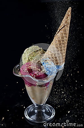 Fruit ice cream scoops overhead on a cornet, served with several colorful spoons isolated on black background Stock Photo