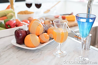 Fruit and fruit juice on marble counter in kitchen room. Apple and orange juice and vegetable on table. Food and drinks concept. Stock Photo