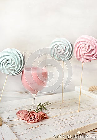 Fruit milkshake, sweet meringue desserts and tender flowers on a wooden coarse tray. light tender still life. summer snack Stock Photo