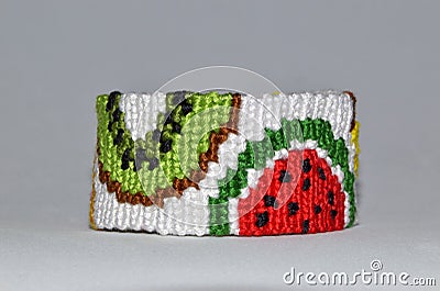 Fruit pattern of braided friendship bracelet handmade of thread isolated on gray background Stock Photo