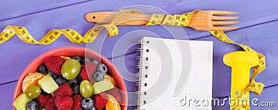 Fruit salad, centimeter with dumbbells and notepad for writing notes, healthy lifestyle and nutrition concept Stock Photo