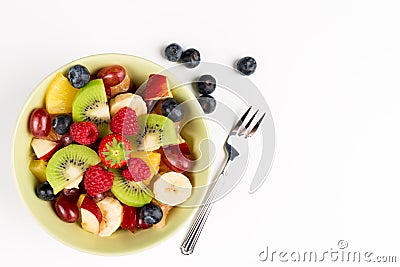 Fruit Salad in Green Bowl, blueberries and fork on white Table, Top View. copy space Stock Photo