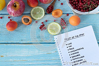 Fruit of the Spirit handwritten words in notebook from Galatians Bible Book on wooden table with fresh colorful fruit, top view Stock Photo