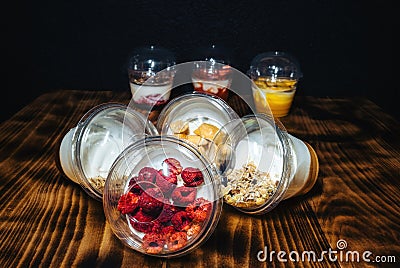 Fruit yogurts on black background. Healthy breakfast on the wooden table. Stock Photo