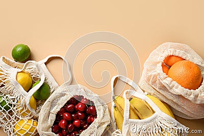 Fruits and citrics in eco-friendly mesh bags on beige background. Zero waste shopping. Stock Photo