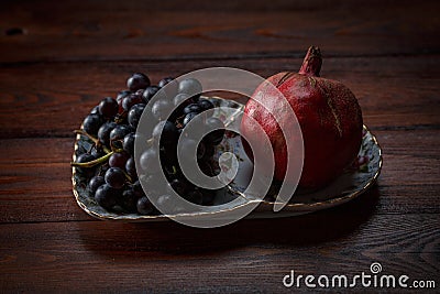 Fruits on a plate, grapes and pomegranate Stock Photo