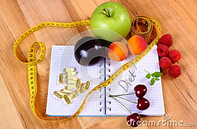 Fruits, tablets supplements and centimeter with notebook, slimming and healthy food Stock Photo