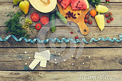 Fruits, vegetables, measure tape, pills on wooden background. Concept of different ways to lose weight. Stock Photo