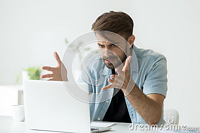 Angry man disagree with fake online news looking at laptop Stock Photo