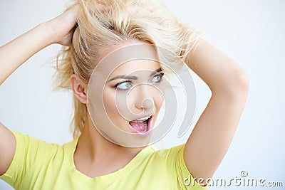 Frustrated blond woman mussing up her long hair Stock Photo